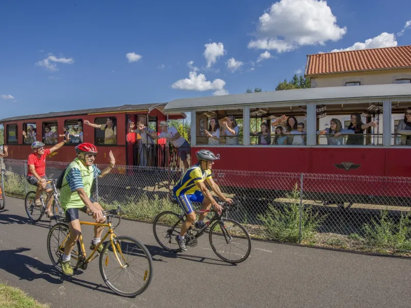 Cyclistes sur l'itinéraire Via Fluvia à côté du train du Velay Express