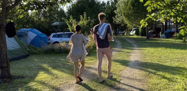 un homme et une femme, serviette sur l'épaule, vue de dos en marchant dans le camping.